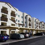 property-flamingo-square Flamingo Pines three story apartment community with dark brown roof tops and balconies and a beige building.