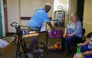 African american woman giving a caucasian woamn in the community food from the Food Pantries at Senior Communities